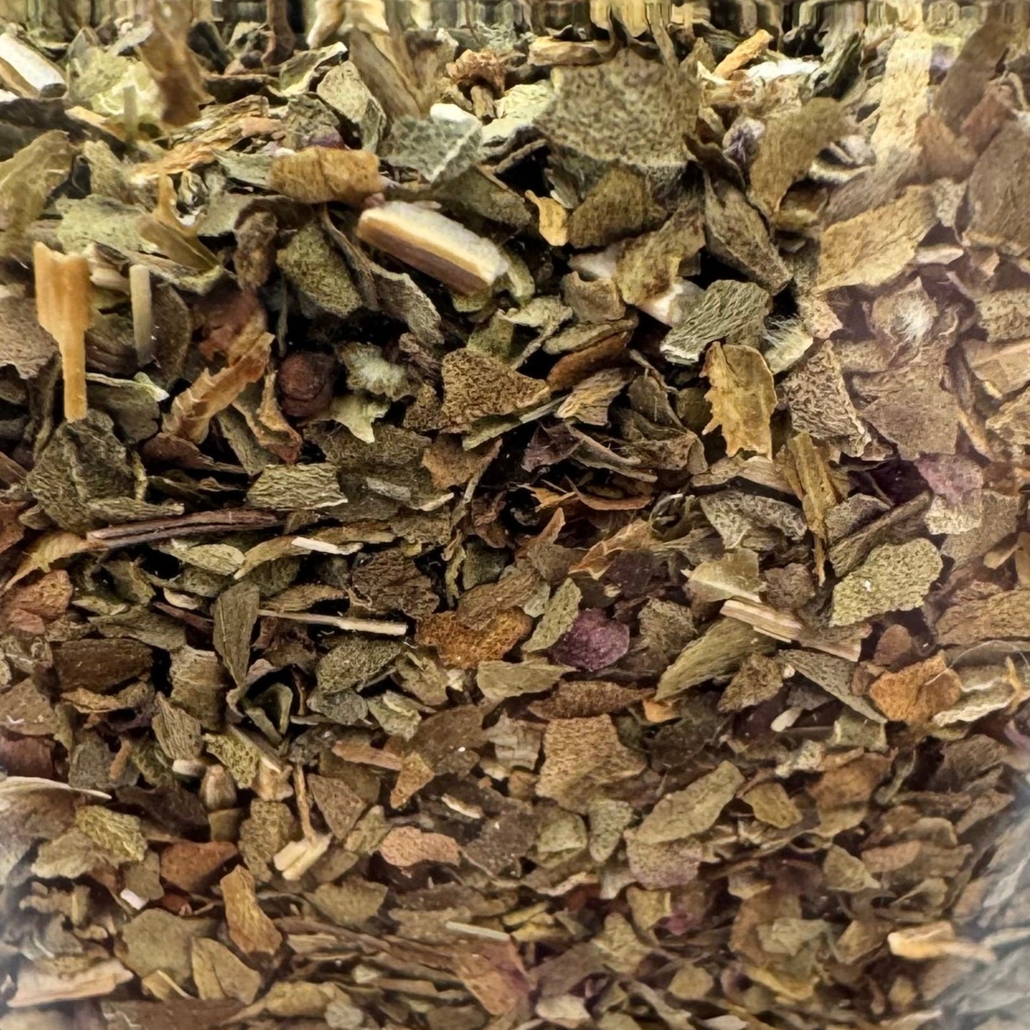 Clear container filled with dried herbs on a light background