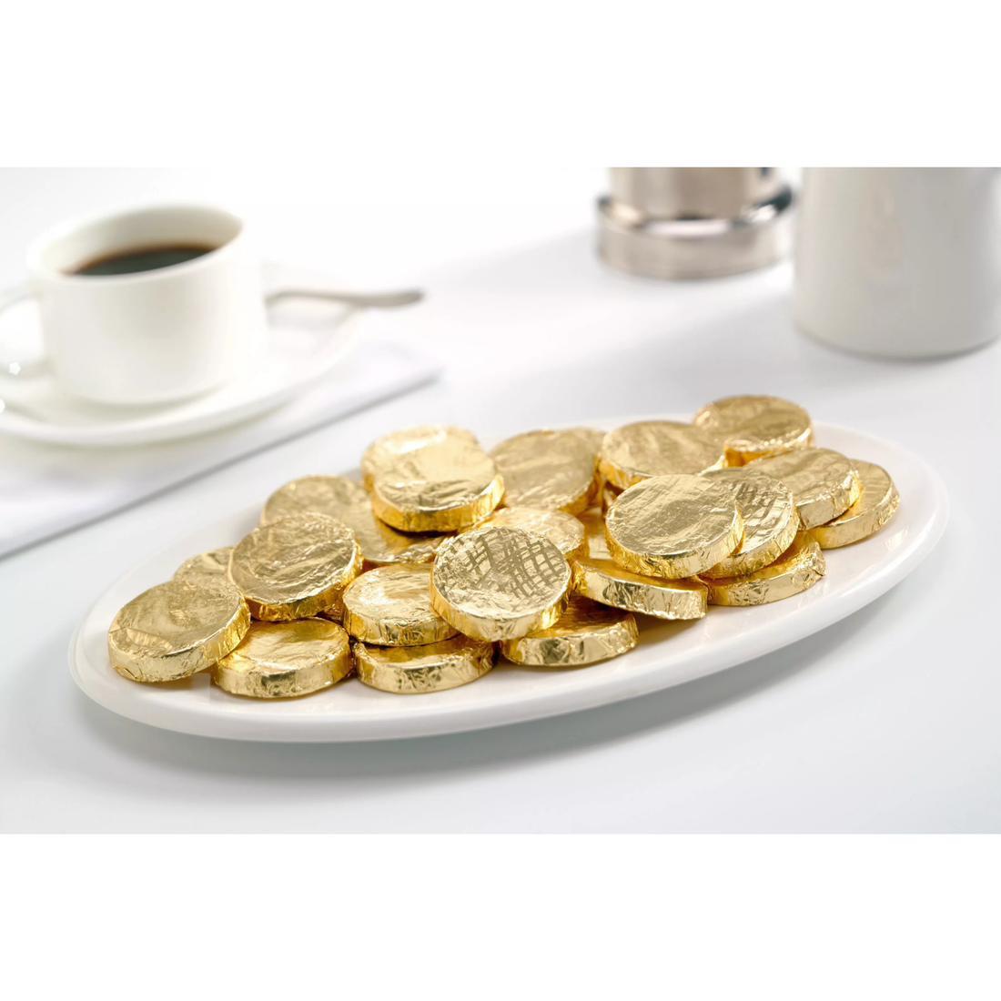 Gold-wrapped chocolate coins with a couple of unwrapped ones on a white background